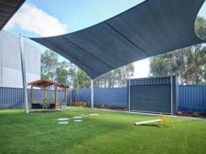 Shed and shade sail in outdoor play space of childcare centre